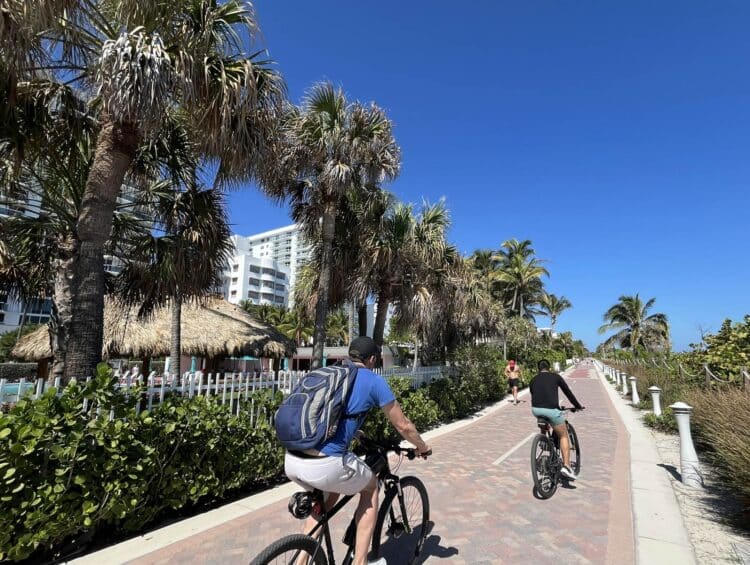 Cyclists riding along a tropical paved pathway